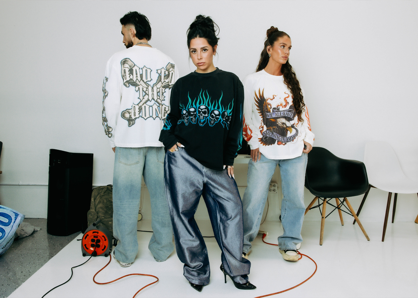 Three models in a white studio wearing Commons Studios streetwear long-sleeves with graphic prints, showcasing the label's editorial art direction.